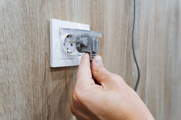 A diligent individual is meticulously focusing on inserting an electrical plug into the nearest...