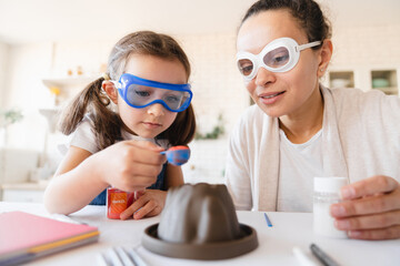 Home science experiment of volcano with baking soda. Eruption for Kid. Daughter with mother making...