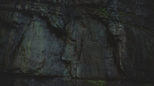 Young woman is standing in awe of a giant basaltic rock formation while exploring a remote, tropical island in the south pacific
