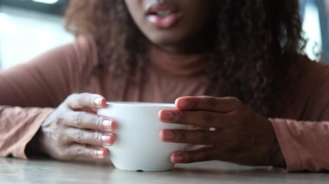 Women's hands hold a mug of hot tea in the morning during the cold season. A young woman warms her hands on a very hot cup of tea.
