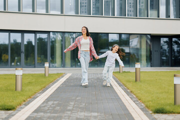 European young mother and daughter confidently walk down the street