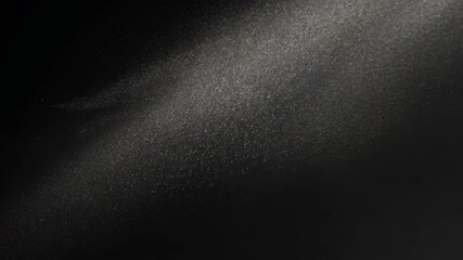 A stream of white particles falls against a dark background - Powered by Adobe