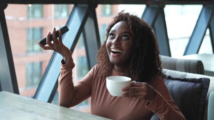 A very beautiful African American woman with long hair listens to a voice message on a smartphone...