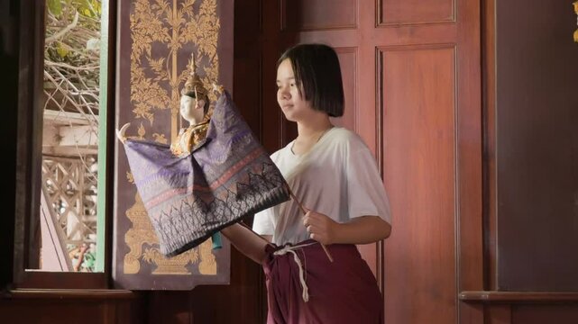 Young Asian girl practice Traditional Thai Puppet at wooden church in Thai temple, Pubic place for everyone in community around temple can use for activity.