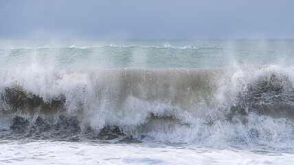 Obraz premium The ocean is rough and the waves are crashing against the shore. The sky is cloudy and the water is a deep blue color