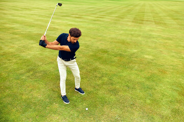Obraz premium A Young Golfer Enthusiastically Swinging a Golf Club on a Lush and Vibrantly Green Field