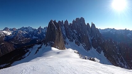 A panoramic view of a snow-capped mountain range with a bright sun shining in the background.