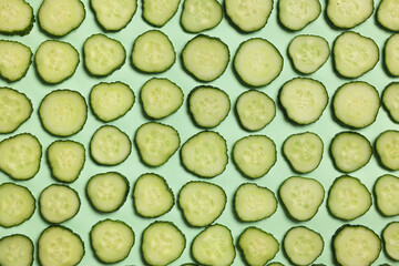 Slices of fresh cucumbers on turquoise background, flat lay