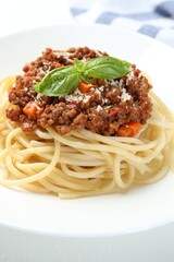 Tasty pasta bolognese with basil on white table, closeup