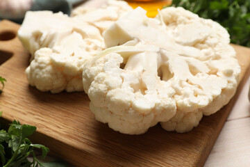 Uncooked cauliflower steaks and parsley on table, closeup