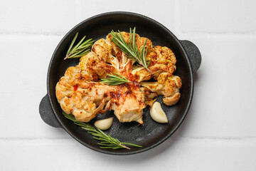 Delicious baked cauliflower steaks on white tiled table, top view