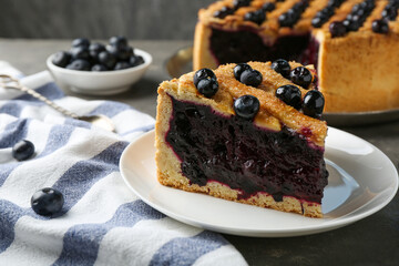 Slice of delicious homemade blueberry pie served on grey table, closeup