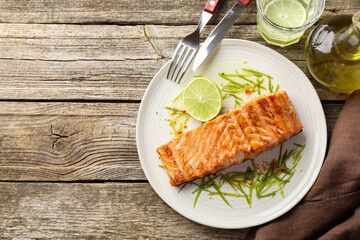 Delicious grilled salmon fillet served on wooden table, flat lay. Space for text