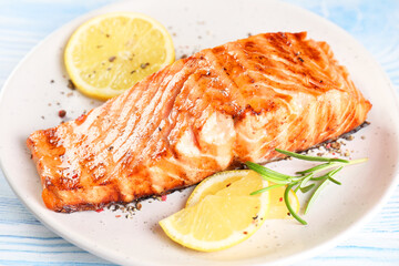 Delicious grilled salmon fillet served on light blue wooden table, closeup