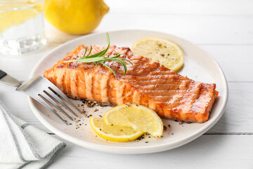 Delicious grilled salmon fillet served on white wooden table, closeup