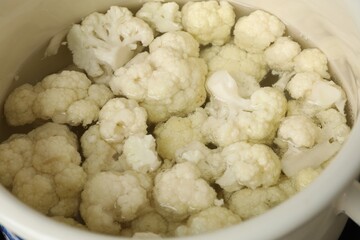 Cooking cauliflower. Florets in white pot with water, closeup