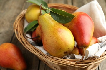 Ripe juicy pears in wicker basket on table, closeup