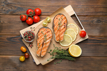 Tasty grilled salmon steaks with peppercorns and products on wooden table, flat lay
