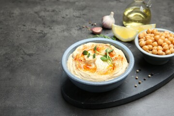 Delicious hummus with paprika served on dark grey table, space for text