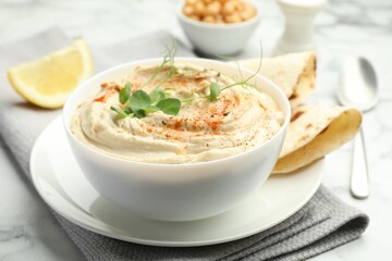 Delicious hummus with paprika and pita on white marble table, closeup