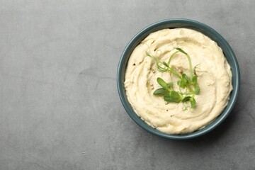 Delicious hummus in bowl and pita on grey table, top view. Space for text