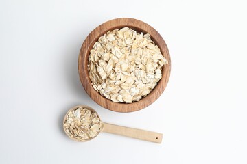 Oat flakes in bowl and spoon isolated on white, top view