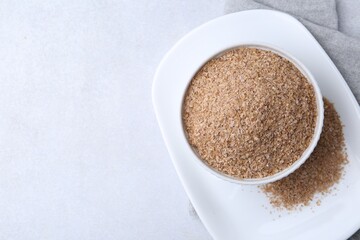 Buckwheat bran in bowl on light grey table, top view. Space for text
