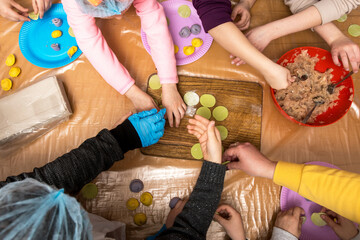 Children aged 7-10 participating in a hands-on cooking class, learning to make ravioli or dumplings. The kids are excitedly shaping dough, enjoying a fun and educational culinary experience