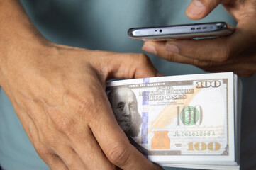 Businessman holding dollars and using smartphone to exchange money