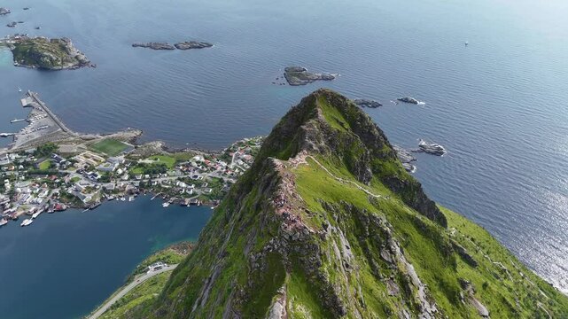 hiking in norway during during summer with midnight sun. Sun is falling behind the mountains on the famous reinebringen hike and little town called reine in 4K.