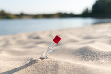 Testing water of river beach. Laboratory test tube on sand on river beach in sunny day