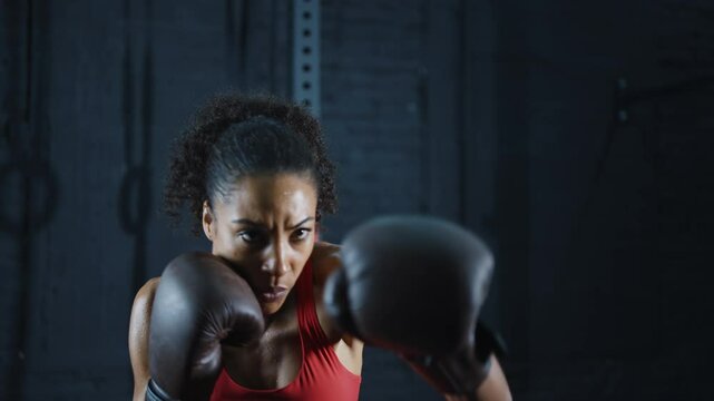 Cinematic video of a fit young woman training in the gym with weights and aerobic exercises. Boxer Woman doing shadow boxing workoutin the fitness club.