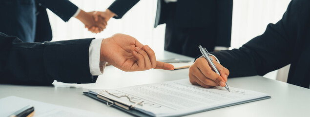 Two business executive shake hand in boardroom, sealing agreement merging two company. Handshake symbolize business partnership and cooperation. Corporate acquisition and merger concept. Shrewd