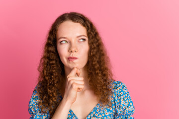 Thoughtful woman with curly hair against a pink background