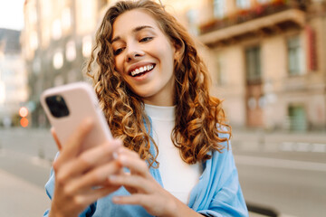 Young woman walking around old street and using smartphone. Online Communication with friends. Technology, connection, blogging, modern lifestyle concept.