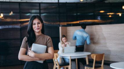 A woman is standing in front of a table with a laptop and a tablet
