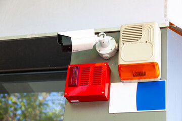 Alarm devices and a video camera hanging on the wall of the building.