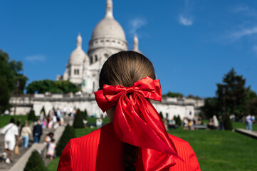 Tourist Girl with red bow in her hair is watching Basilica of Sacre Coeur de Montmartre, commonly known as Sacre-Coeur Basilica, in Paris