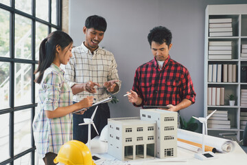 Architects are discussing a project using a model of a building and digital tablet