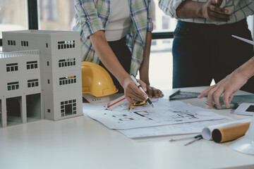 Architects team working together on a project in the office using a blueprint and pointing at it...
