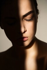 Shadowed Serenity: A young woman's face, partially obscured by a dramatic shadow, evokes a sense of pensive calm and quiet contemplation. The image is a study in light and shadow.