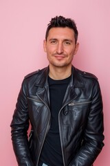 Obraz premium Confident Young Man in Black Leather Jacket Against Soft Pink Background