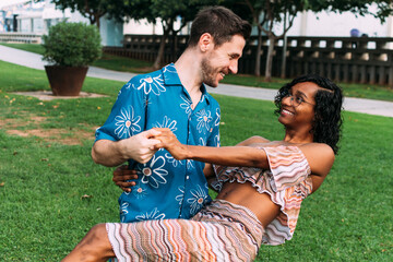 Young interracial couple holding hands, dancing and having fun in the park. Transgender woman.