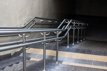 There is a long row of stainless steel handrails along a staircase