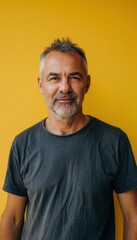 Obraz premium Relaxed Mature Man Against Yellow Background - Portrait for Professional Use and Design