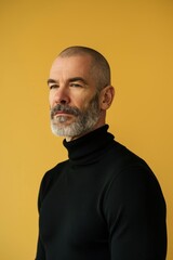 Obraz premium Professional Portrait of a Confident Man in Black Turtleneck Against Yellow Background