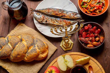 Challah, honey, apple and pomegranate and wine and chelnt with dried fruits on the table with...