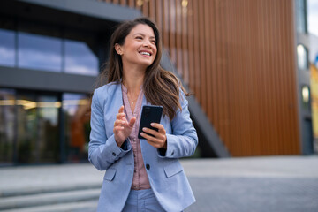 Portrait of business woman holding phone in hands standing outdoor 