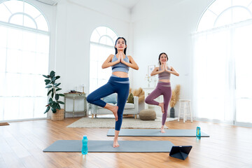 Obraz premium Couple Asian women exercise together with yoga posture by stand and hands together also stay on mat in room with day light.