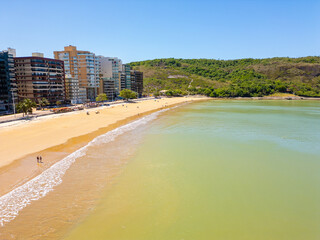 Imagem aérea de drone da Praia do Morro em um dia ensolarado, com pessoas passeando, praticando esportes e descansando ao sol. Cidade de Guarapari no Espírito Santo